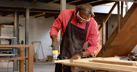 Skilled Artisan Cutting Wooden Plank with Jigsaw in Workshop