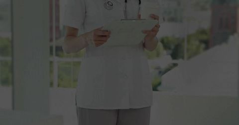 Nurse Holding Clipboard in Sunlit Hospital Corridor