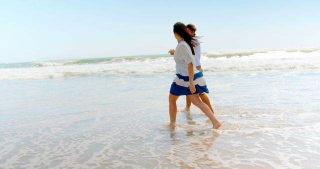 Happy caucasian couple holding hands and walking on beach, copy space. Relationship, togetherness, summer, leisure, vacation and lifestyle, unaltered.