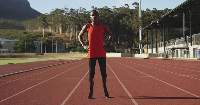 Portrait of african american male athlete with prosthetic legs training at empty stadium. Sport, disability, athletics, training and fitness, unaltered.