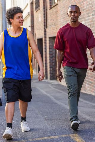 African american men walking and talking in urban brick alleyway wearing casual streetwear