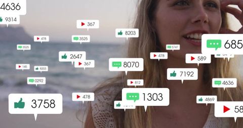 Smiling blonde woman touching hair on beach with floating media notifications at dusk