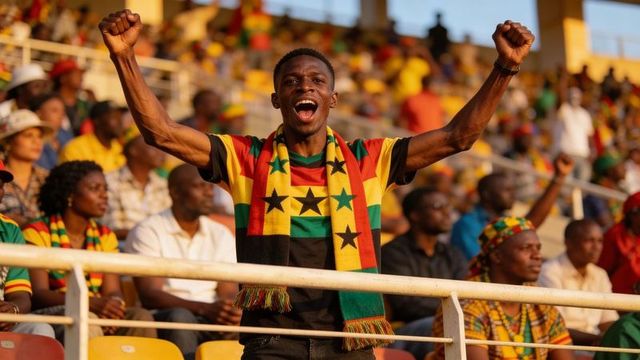 Triumphant fan cheering and raising fists in stadium wearing flag scarf and wristwatch