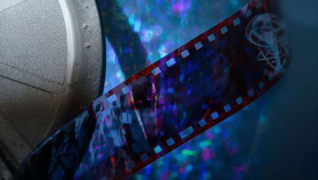 Curving 35mm film strip with metal canister and iridescent blue bokeh reflection