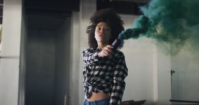 Confident Woman Holding Green Smoke Bomb in Industrial Space - Download Free Stock Images Pikwizard.com