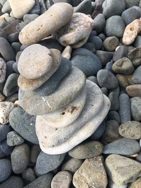 Balanced pile of smooth, gray rocks evokes feelings of peace and stability. Perfect for promoting relaxation and mindfulness in advertisements, blog posts about meditation, or environmental awareness campaigns.