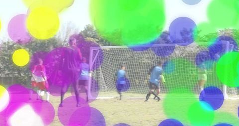 Youth soccer players crowding goal while goalkeeper defending with colorful bokeh overlay