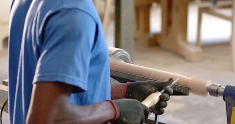 Craftsman shaping wood cylinder on lathe with precision