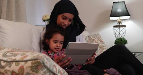 Mother and daughter bonding on sofa with tablet