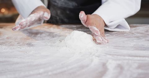 Baker kneading dough on floured counter in artisan bakery