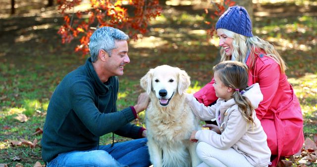 Happy family spending a joyful autumn day outdoors in a park with their golden retriever. Parents and daughter are bonding and smiling, creating a warm and happy atmosphere. Ideal image for articles on family activities, autumn fun, pet companionship, and outdoor leisure. Suitable for use in family-oriented advertising, seasonal promotions, and pet-related content.