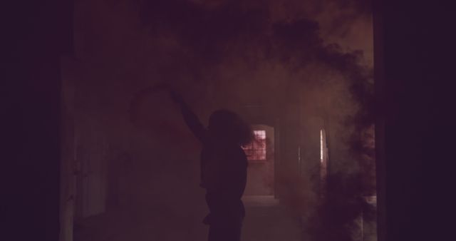 Silhouetted figure in a smoky room, with copy space. Mystery shrouds the scene as the person appears amidst the haze indoors.