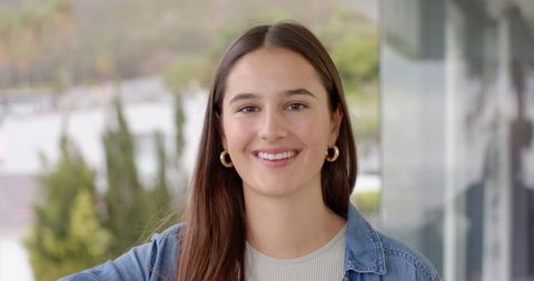 Young woman smiling wearing denim jacket and gold hoop earrings
