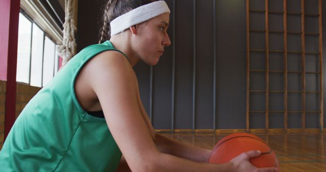 Caucasian female basketball player resting and holding ball. basketball, sports training at an indoor court.