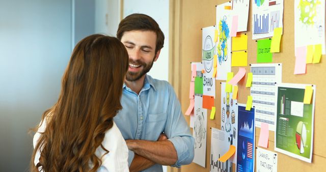 Smiling coworkers discussing project ideas on cork board in creative office - Download Free Stock Images Pikwizard.com