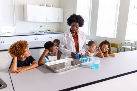 African american teacher demonstrating colorful science experiment to curious school children