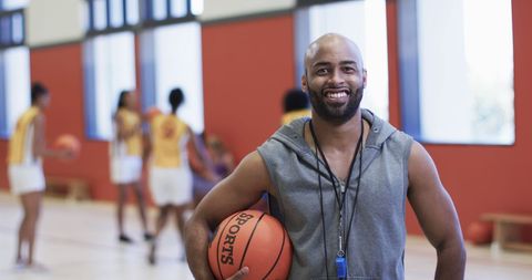 Smiling Basketball Coach Holding Ball on Indoor Court - Download Free Stock Images Pikwizard.com