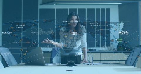 Presenting midadult executive leaning, gesturing at boardroom table with holographic world map