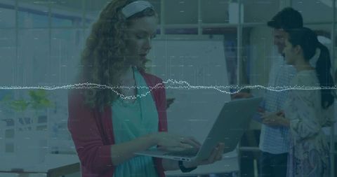 Woman typing in modern office with colleagues brainstorming background