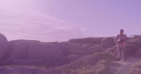 Asian woman hiking coastal trail with yoga mat at sunrise walking outdoors