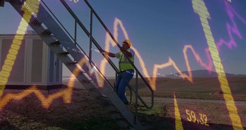 Technician climbing stairs gripping handrail on rural wind site with financial chart overlay