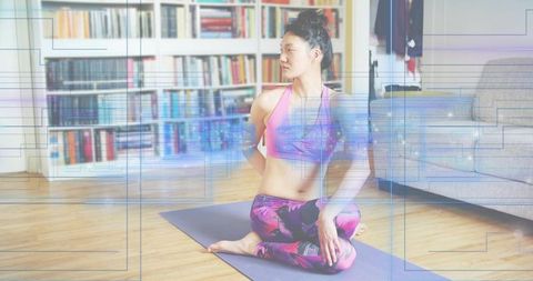 Korean woman practicing seated spinal twist on purple yoga mat in sunlit living room