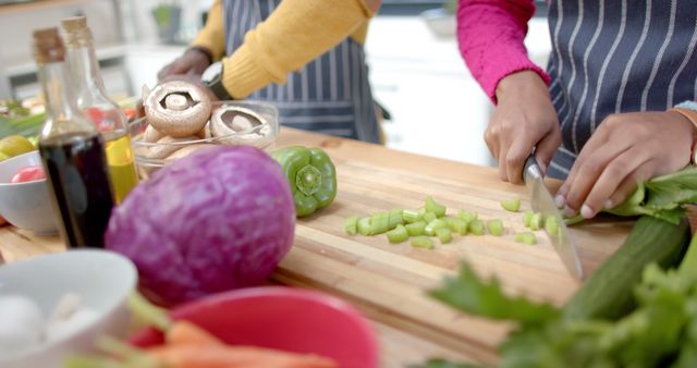 Depicts hands chopping vegetables in a kitchen. Great for illustrating healthy food preparation, cooking at home, and cooking tutorials. Perfect for use in blogs, cookbooks, and food-related websites.
