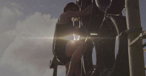 Woman climbing obstacle course with tire and wooden framework