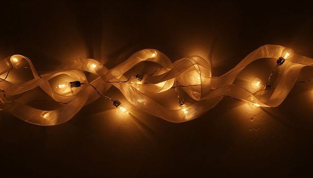 Warm ribbon string lights casting layered shadows and golden glow on dark wall