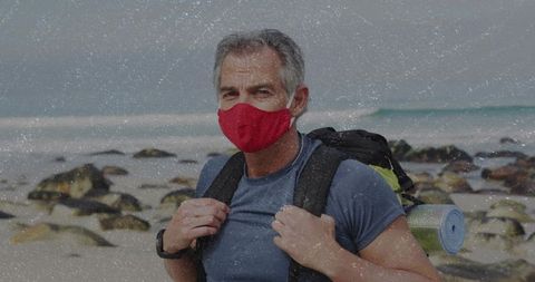 Masked adventurer trekking rocky beach coastline