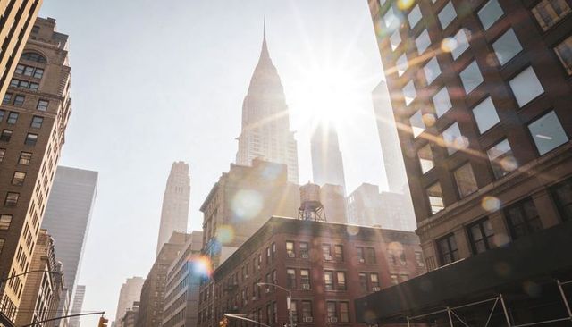 Sunlight flooding manhattan skyline casting dramatic lens flare on spire-topped skyscraper