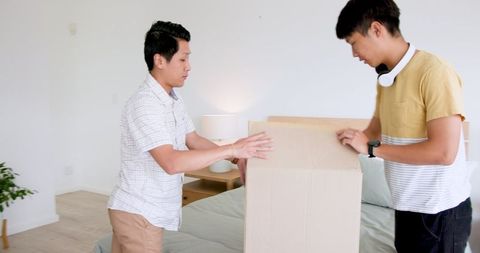 Father and Son Teamwork While Unpacking Cardboard Box
