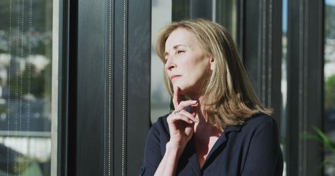 Thoughtful woman looking through office window