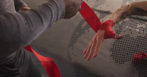 Trainer wrapping red hand wrap on athlete wrist preparing for boxing session