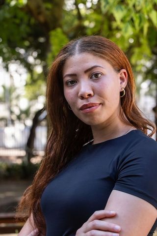 Confident african american woman standing with crossed arms in urban park portrait