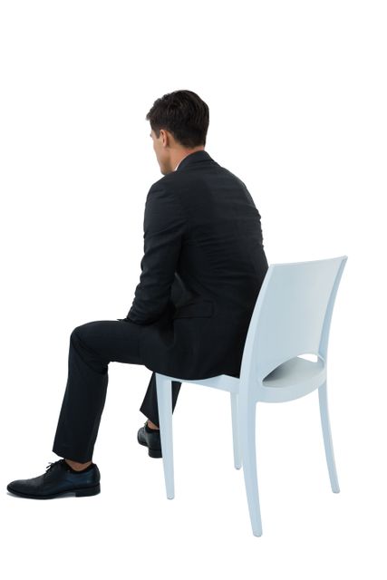 This image shows a businessman in formal attire sitting on a chair, viewed from the back against a white background. It can be used for corporate presentations, business-related articles, office decor, or professional websites to convey themes of professionalism, contemplation, or workplace environment.