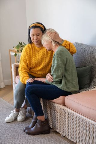 Comforting friend on cozy rattan sofa showing empathy, support and companionship
