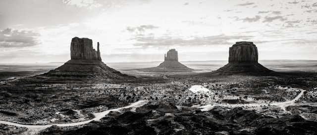 Close-up panoramic view of Monument Valley capturing distinctive buttes and vast desert plains in black and white. Great for articles, travel blogs, educational content about geological formations, and prints highlighting natural beauty and iconic American landscapes.