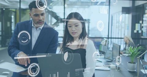 Professionals analyzing data on laptop in modern office