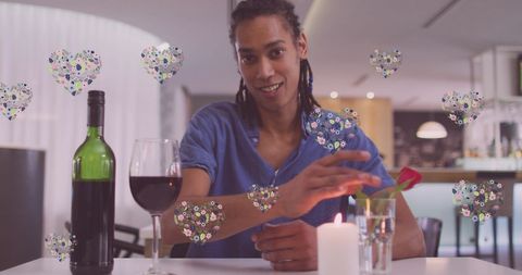 Smiling man having virtual date in modern setting with heart icon overlays