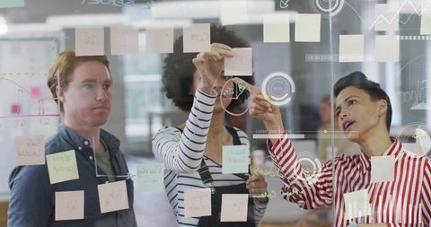 Creative team brainstorming on glass wall with sticky notes and hud overlays