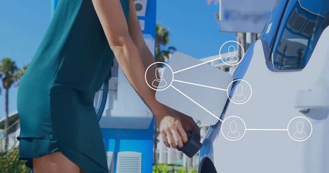 Woman Charging Electric Vehicle at Station in Urban Area