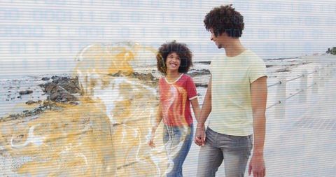 Joyful couple holding hands while walking by the seaside
