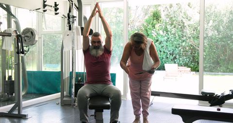 Senior couple exercising together with tablet guidance in gym