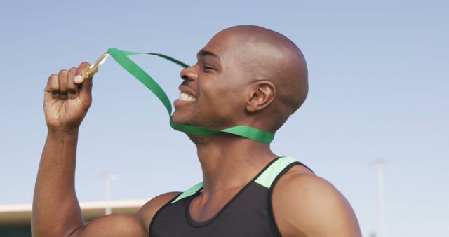 An African American athlete is joyfully biting a gold medal, with copy space - Download Free Stock Photos Pikwizard.com