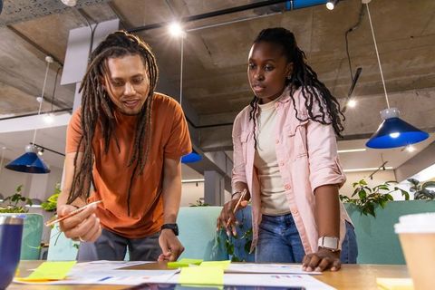 Diverse creative team collaborating and brainstorming over sticky notes in modern open-plan office