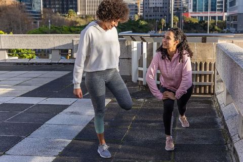 Sunlit rooftop stretching session with diverse women balancing and smiling