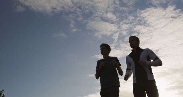 Silhouette of Two Men Jogging at Dawn Under Cloudy Sky - Download Free Stock Images Pikwizard.com