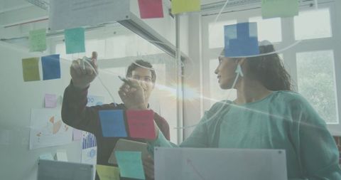 Team collaborating on strategies using transparent board with sticky notes