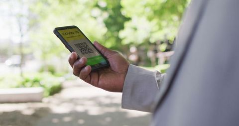 Man Holding Smartphone with COVID-19 Passport in Urban Setting